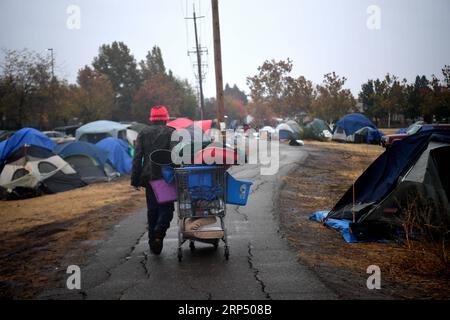 (181122) -- BUTTE, Nov. 22, 2018 (Xinhua) -- A resident walks with his belongings among the tents at a parking lot in Chico of Butte County, California, the United States, Nov. 21, 2018. Local officials warned that the rain after the wildfire could cause risk of flash floods and mudflows. (Xinhua/Wu Xiaoling)(clq) U.S.-CALIFORNIA-BUTTE-WILDFIRE-RAIN PUBLICATIONxNOTxINxCHN Stock Photo