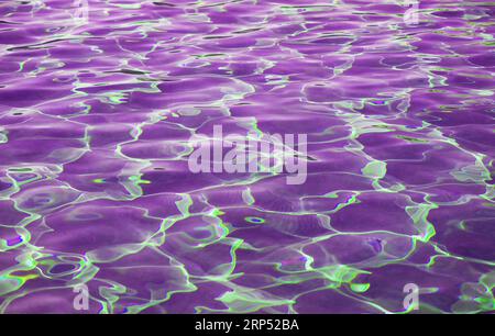 Stunning surreal pop art of purple colored water surface reflecting with sunlight Stock Photo