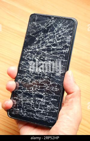 Hand holding a phone with broken screen Stock Photo