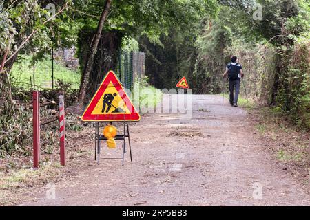 A trakker walking through a road where work in progress signs are placed. Stock Photo