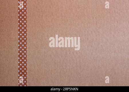 background of brown craft paper and a strip of brown craft tape with small white dots on the left side of the image Stock Photo