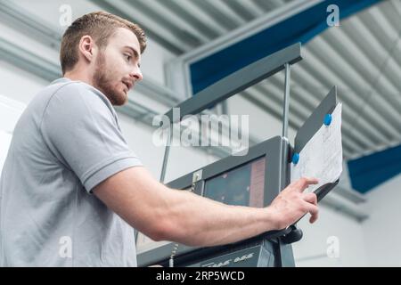 Worker entering data on screen of a modern machine tool in factory Stock Photo