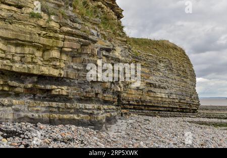 This cliff face on a welsh beach shows what the effects of coastal  erosion and weather can do over time to the layers of rock supporting it. Stock Photo