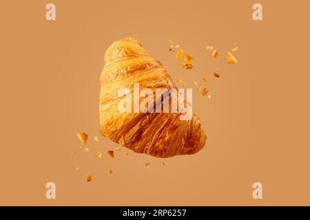 Freshly baked croissant flying in air. Close up of crumbled french croissant. Stock Photo