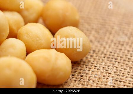 Shelled macadamia nuts on a rough rustic burlap. Nutritious diet food. Macro shot Stock Photo