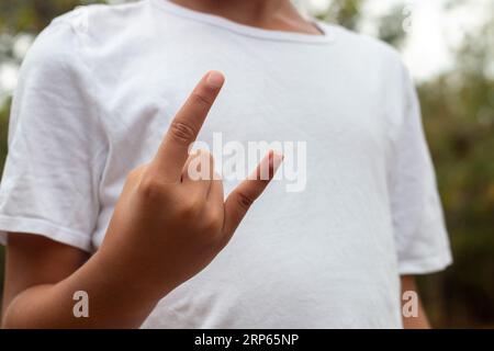 Child's hand making different shapes, either raising a finger, raising a fist or making a surfer salute Stock Photo