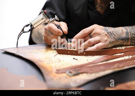 (190108) -- FLORENCE (ITALY), Jan. 8, 2019 -- An exhibitor carves on a belt during the 95th Pitti Immagine Uomo exhibition in Florence, Italy, Jan. 8, 2019. The exhibition, one of the world s most important platforms for men s clothing and accessory collections, is held here from Jan. 8 to 11. ) ITALY-FLORENCE-MEN S CLOTHING AND ACCESSORY-EXHIBITION ChengxTingting PUBLICATIONxNOTxINxCHN Stock Photo