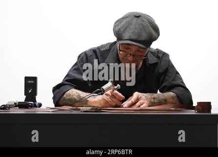 (190108) -- FLORENCE (ITALY), Jan. 8, 2019 -- An exhibitor carves on a belt during the 95th Pitti Immagine Uomo exhibition in Florence, Italy, Jan. 8, 2019. The exhibition, one of the world s most important platforms for men s clothing and accessory collections, is held here from Jan. 8 to 11. ) ITALY-FLORENCE-MEN S CLOTHING AND ACCESSORY-EXHIBITION ChengxTingting PUBLICATIONxNOTxINxCHN Stock Photo