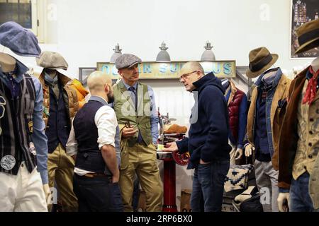 (190108) -- FLORENCE (ITALY), Jan. 8, 2019 -- A visitor (R) talks with exhibitors during the 95th Pitti Immagine Uomo exhibition in Florence, Italy, Jan. 8, 2019. The exhibition, one of the world s most important platforms for men s clothing and accessory collections, is held here from Jan. 8 to 11. ) ITALY-FLORENCE-MEN S CLOTHING AND ACCESSORY-EXHIBITION ChengxTingting PUBLICATIONxNOTxINxCHN Stock Photo
