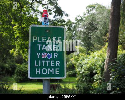Please take your litter home sign with litter on top Stock Photo