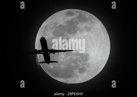 (190122) -- BEIJING, Jan. 22, 2019 (Xinhua) -- A plane flies past the super moon in Los Angeles, the United States, Jan. 20, 2019. (Xinhua/Qian Weizhong) XINHUA PHOTOS OF THE DAY PUBLICATIONxNOTxINxCHN Stock Photo