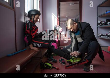 (190201) -- BEIJING, Feb. 1, 2019 (Xinhua) -- Photo taken on Jan. 9, 2019 shows head teacher Ding Jianpei (R) helping a student with the skating shoes for a training session at Taipingzhuang Central Primary School, in Yanqing District of Beijing, capital of China. Taipingzhuang Central Primary School situated right at the foot of Xiaohaituo Mountains, where the venues for Beijing 2022 Winter Olympic games are under construction. Teachers of Taipingzhuang Central Primary School have turned an experimental farmland into a seasonal skating rink for the pupils here to learn skating since 2016. The Stock Photo