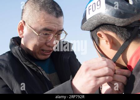 (190201) -- BEIJING, Feb. 1, 2019 (Xinhua) -- Photo taken on Jan. 23, 2019 shows head teacher Ding Jianpei (L) helps a boy, Zhang Heyan, with his helmet in preparation for a training session at Taipingzhuang Central Primary School, in Yanqing District of Beijing, capital of China. Taipingzhuang Central Primary School situated right at the foot of Xiaohaituo Mountains, where the venues for Beijing 2022 Winter Olympic games are under construction. Teachers of Taipingzhuang Central Primary School have turned an experimental farmland into a seasonal skating rink for the pupils here to learn skatin Stock Photo