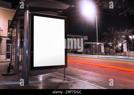 Blank advertisement bus shelter with blurred traffic lights night Stock Photo