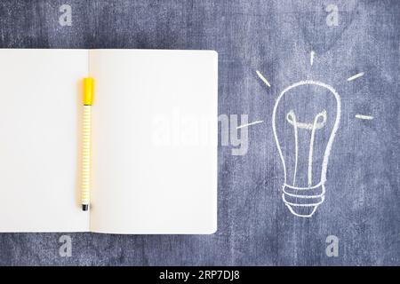 Felt tip pen blank notebook with drawn light bulb chalkboard Stock Photo