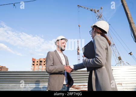 Smiling engineers shaking hands construction site architectural project Stock Photo