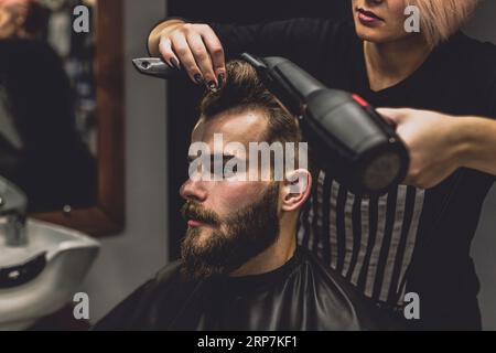 Barber woman drying hair client Stock Photo