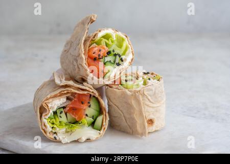 Tortilla with salmon, creamy cheese and vegetables on white plate Stock Photo