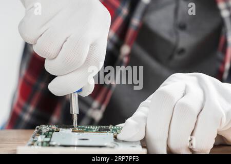 Technician repairing computer motherboard with screwdriver Stock Photo