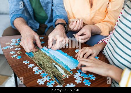 Close up people doing puzzle together Stock Photo - Alamy