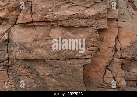 Peach coloured stone background with some cracks  and at various levels Stock Photo