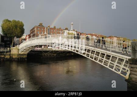 A view of the Ha'penny Bridge in Dublin on a winter's day of sunshine, rainbow and showers. Dublin, Ireland Stock Photo