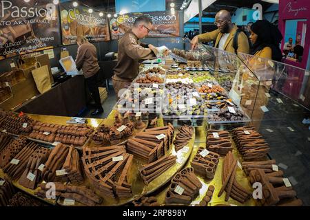 (190222) -- BRUSSELS, Feb. 22, 2019 -- Visitors select chocolates at the 6th edition of the Chocolate Fair in Brussels, Belgium, on Feb. 22, 2019. The 6th edition of the Chocolate Fair (Le Salon du Chocolat) kicked off in Brussels on Thursday. More than 130 chocolatiers, pastry chefs, confectioners, designers and cocoa experts are here to share and exhibit chocolate in all its delectable forms. ) BELGIUM-BRUSSELS-CHOCOLATE FAIR ZhengxHuansong PUBLICATIONxNOTxINxCHN Stock Photo