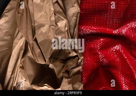 Close-up of brown crumpled packing paper and a red woven plastic net for packaging food products. Abstract close-up background. Stock Photo