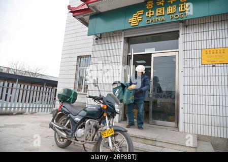 (190226) -- CHANGCHUN, Feb. 26, 2019 (Xinhua) -- Postman Jin Renzhe carries postal packages to be loaded on his motorbike at the township branch of China Post in Chunhua Township of Huichun City, northeast China s Jilin Province, Feb. 19, 2019. Jin Renzhe has been working as a postman for 30 years in Chunhua Township, where postal service is inadequate because of steep mountain paths and loosely-scattered villages. Despite that, Jin manages to deliver mails to villagers the same day mails arrive in the town. As many young people work outside the town, Jin bridges them and their parents through Stock Photo