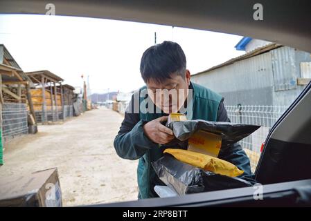 (190226) -- CHANGCHUN, Feb. 26, 2019 (Xinhua) -- Postman Jin Renzhe unloads postal packages in Chunhua Township of Huichun City, northeast China s Jilin Province, Feb. 19, 2019. Jin Renzhe has been working as a postman for 30 years in Chunhua Township, where postal service is inadequate because of steep mountain paths and loosely-scattered villages. Despite that, Jin manages to deliver mails to villagers the same day mails arrive in the town. As many young people work outside the town, Jin bridges them and their parents through delivering packages. Living with eye disease and arthritis, Jin st Stock Photo