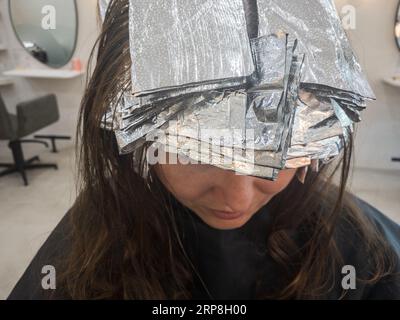Woman with hair foils in her hair. Bleaching or dyeing process at hair salon. Stock Photo