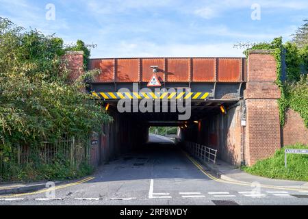 Red brick and iron railway bridge over a road Stock Photo