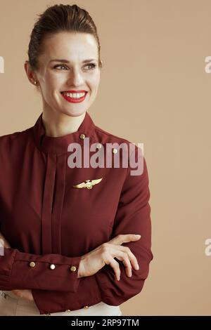 happy modern air hostess woman against beige background looking at copy space. Stock Photo