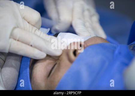 (190402) -- PHNOM PENH, April 2, 2019 (Xinhua) -- Doctor Liang Hao of the First Affiliated Hospital of Guangxi Medical University applies an eye patch to Sum Meyle s left eye after a cataract operation at Kampong Cham Provincial Hospital in Kampong Cham, Cambodia, March 15, 2019. Sum Meyle, 36, is a single mother with five children. To help improve their financial conditions, two of Meyle s daughters are now working in the capital Phnom Penh while two of her sons are living in a children s nursing home. Meyle now lives in a rented shanty house with her youngest daughter. Meyle had suffered fro Stock Photo