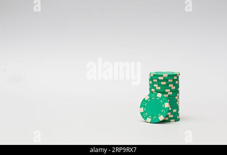 Green casino chips stacked on white background. Poker game. Stock Photo