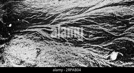 Background: nature's art graphic resource. Light and dark coloured sands on a beach in low key black and white. Looks like a river delta from high up. Stock Photo