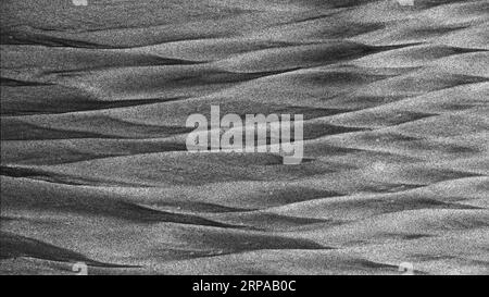 Background: nature's art graphic resource. A monochrome scene of black volcanic and golden sands mixed into diamond shapes by the sea on a beach Stock Photo