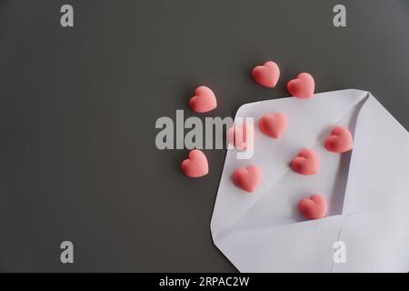 Pink hearts and envelope on black background, flat lay with copy space. Love letter, valentine's day concept Stock Photo