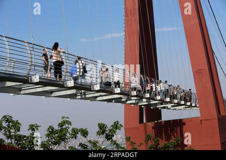 (190505) -- WUXI, May 5, 2019 (Xinhua) -- Tourists walk on a glass bridge at the Huaxi World Adventure Park in Huaxi Village of Jiangyin City, east China s Jiangsu Province, May 4, 2019. The 518-meter-long glass bridge hangs more than 100 meters above ground level at the park. It is made of panes of 35-mm-thick glass. Each glass can hold a maximum weight of 4.7 tonnes. Around 2,600 people can cross the bridge at a time. (Xinhua/Xu Congjun) CHINA-JIANGSU-JIANGYIN-GLASS BRIDGE (CN) PUBLICATIONxNOTxINxCHN Stock Photo