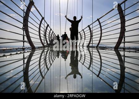 (190505) -- WUXI, May 5, 2019 (Xinhua) -- Tourists walk on a glass bridge at the Huaxi World Adventure Park in Huaxi Village of Jiangyin City, east China s Jiangsu Province, May 4, 2019. The 518-meter-long glass bridge hangs more than 100 meters above ground level at the park. It is made of panes of 35-mm-thick glass. Each glass can hold a maximum weight of 4.7 tonnes. Around 2,600 people can cross the bridge at a time. (Xinhua/Xu Congjun) CHINA-JIANGSU-JIANGYIN-GLASS BRIDGE (CN) PUBLICATIONxNOTxINxCHN Stock Photo