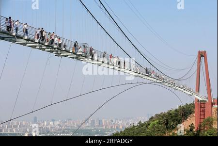 (190505) -- WUXI, May 5, 2019 (Xinhua) -- Tourists walk on a glass bridge at the Huaxi World Adventure Park in Huaxi Village of Jiangyin City, east China s Jiangsu Province, May 4, 2019. The 518-meter-long glass bridge hangs more than 100 meters above ground level at the park. It is made of panes of 35-mm-thick glass. Each glass can hold a maximum weight of 4.7 tonnes. Around 2,600 people can cross the bridge at a time. (Xinhua/Xu Congjun) CHINA-JIANGSU-JIANGYIN-GLASS BRIDGE (CN) PUBLICATIONxNOTxINxCHN Stock Photo