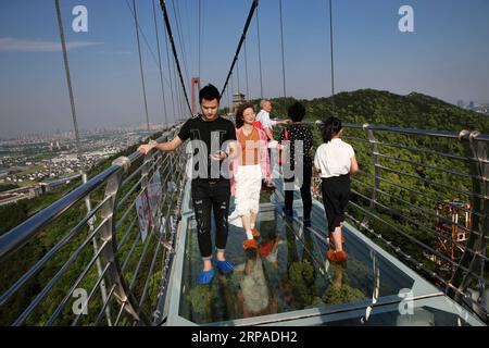 (190505) -- WUXI, May 5, 2019 (Xinhua) -- Tourists walk on a glass bridge at the Huaxi World Adventure Park in Huaxi Village of Jiangyin City, east China s Jiangsu Province, May 4, 2019. The 518-meter-long glass bridge hangs more than 100 meters above ground level at the park. It is made of panes of 35-mm-thick glass. Each glass can hold a maximum weight of 4.7 tonnes. Around 2,600 people can cross the bridge at a time. (Xinhua/Xu Congjun) CHINA-JIANGSU-JIANGYIN-GLASS BRIDGE (CN) PUBLICATIONxNOTxINxCHN Stock Photo