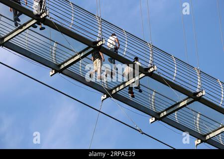 (190506) -- BEIJING, May 6, 2019 (Xinhua) -- Tourists walk on a glass bridge at the Huaxi World Adventure Park in Huaxi Village of Jiangyin City, east China s Jiangsu Province, May 4, 2019. The 518-meter-long glass bridge hangs more than 100 meters above ground level at the park. It is made of panes of 35-mm-thick glass. Each glass can hold a maximum weight of 4.7 tonnes. Around 2,600 people can cross the bridge at a time. (Xinhua/Xu Congjun) XINHUA PHOTOS OF THE DAY PUBLICATIONxNOTxINxCHN Stock Photo