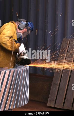 Heavy Industry Engineer using Grinder in Industrial Workshop Stock Photo