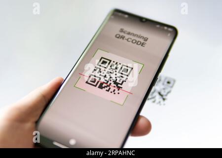 Scanning QR code with mobile smart phone. all the graphics on the screen are made up. Stock Photo