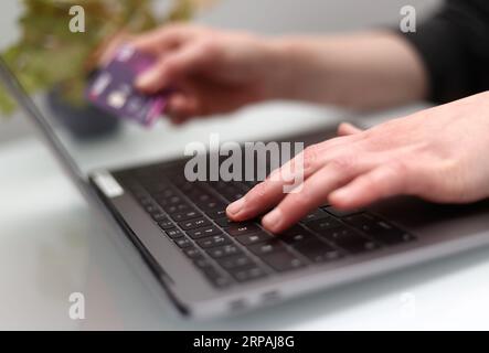 File photo dated 30/03/20 of a woman uses a laptop as she holds a bank card, as a proposal to crack down on hidden charges for online consumers has been put forward by the Government as it says new research shows the practice is widespread. Issue date: Monday September 4, 2023. Stock Photo