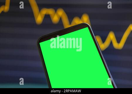 Black phone with blank mockup screen on rising stock graph. Closeup hand showing smartphone isolated green display. Online banking, Fund App use. Fina Stock Photo
