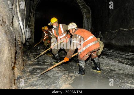 (190516) -- RUOQIANG, May 16, 2019 (Xinhua) -- Construction workers clean mud in the tunnel though Altun Mountains in Ruoqiang County, northwest China s Xinjiang Uygur Autonomous Region, May 15, 2019. The 13.195-kilometer-long tunnel through Altun Mountains is the longest tunnel of the Golmud-Korla railway line. The railway line, connecting Golmud in Qinghai and Korla in Xinjiang, is the third rail artery linking Xinjiang with neighboring provinces. The line will cut the traffic time between Golmud and Korla from 26 hours to 12 hours. (Xinhua/Ding Lei) CHINA-XINJIANG-RAILWAY-TUNNEL-CONSTRUCTIO Stock Photo