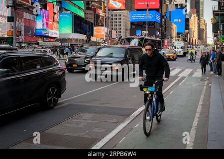 New York City, New York, USA - April 26 2023: Man riding a bike on a busy New York City street. Man not wearing a safety helmet. Stock Photo