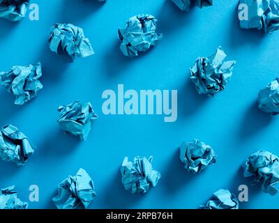 Crumpled blue paper balls on blue background with copy space in the middle. Background, backdrop use for text entry. Stock Photo